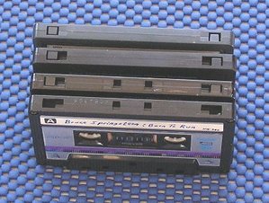 Notches on the top surface of the audio cassette indicate its type.  The top cassette, with only write protect notches (here covered by write protect tabs), is a Type I.  The next cassette down, with additional notches adjacent to the write protect notch, is a Type II.  The bottom two cassettes, featuring the Type II notches plus an additional pair in the middle of the cassette are type IV (metal); note the removal of the write-protect plastic tabs on the second of these.