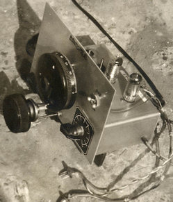 A two-tube homemade radio from 1958. The tubes are the two glass columns with the dark tops. The leads at the bottom connect to the low-voltage filament supply and to the high-voltage anode supply